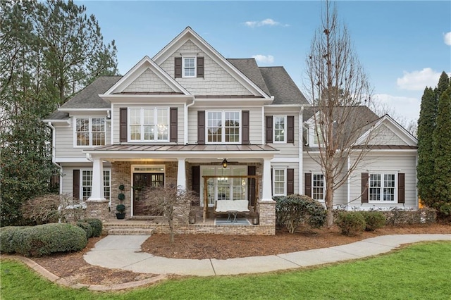 craftsman-style house featuring roof with shingles, a porch, a front lawn, and brick siding