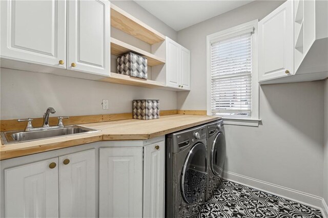 laundry area with independent washer and dryer, a sink, cabinet space, and baseboards