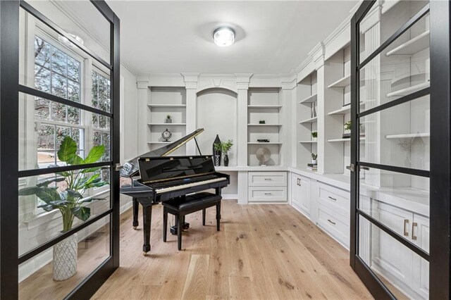 sitting room with light wood-style floors, ornamental molding, and built in shelves