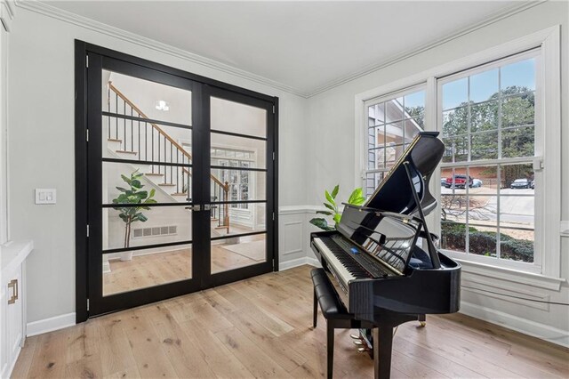 sitting room featuring ornamental molding, light wood-type flooring, visible vents, and stairway