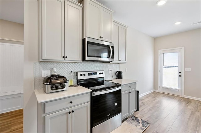 kitchen featuring decorative backsplash, appliances with stainless steel finishes, and light wood-type flooring