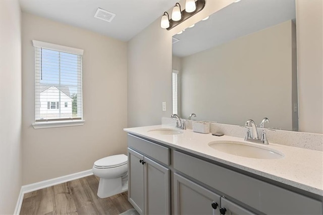 bathroom featuring toilet, hardwood / wood-style flooring, vanity, and a wealth of natural light