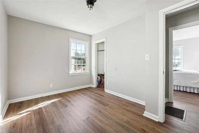 unfurnished bedroom featuring dark hardwood / wood-style floors and multiple windows