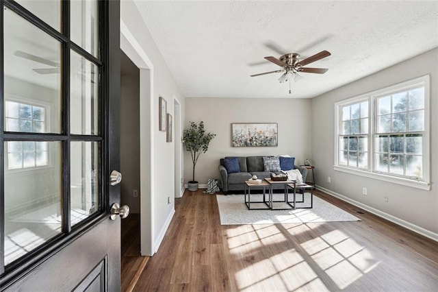 living room featuring ceiling fan, a textured ceiling, and hardwood / wood-style flooring