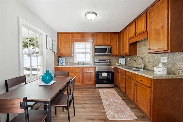 kitchen with appliances with stainless steel finishes, sink, and hardwood / wood-style flooring