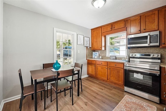 kitchen featuring backsplash, appliances with stainless steel finishes, and light hardwood / wood-style flooring