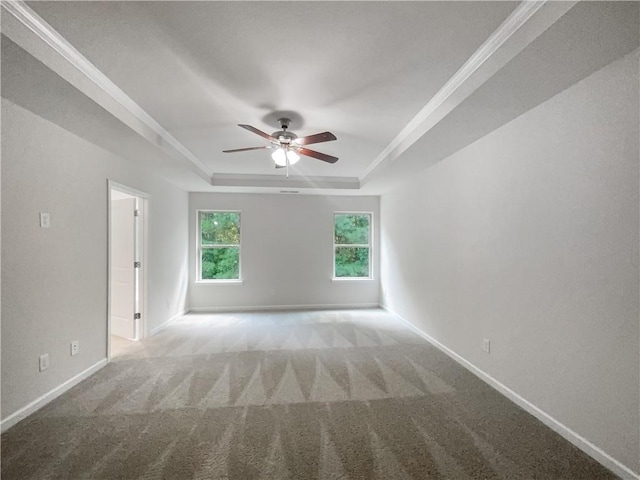 spare room with ceiling fan, ornamental molding, light colored carpet, and a tray ceiling