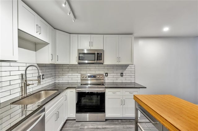 kitchen featuring backsplash, stainless steel appliances, sink, wood-type flooring, and white cabinetry