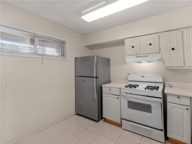 kitchen featuring under cabinet range hood, white cabinets, light countertops, freestanding refrigerator, and white gas range