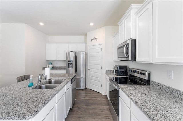 kitchen featuring dark hardwood / wood-style floors, sink, white cabinetry, appliances with stainless steel finishes, and an island with sink