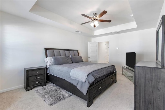 carpeted bedroom featuring ceiling fan and a raised ceiling