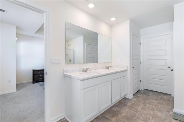 bathroom featuring a shower with shower door and vanity