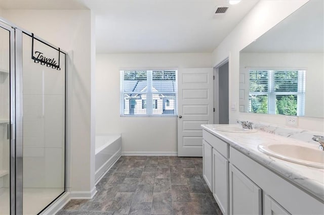 bathroom with a wealth of natural light, separate shower and tub, and vanity