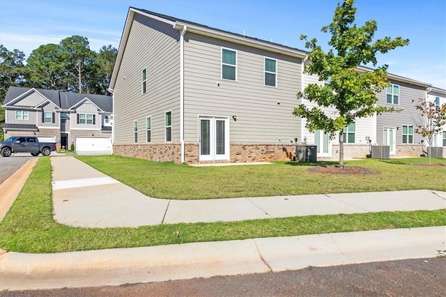 view of front facade with a front lawn, a garage, and central AC