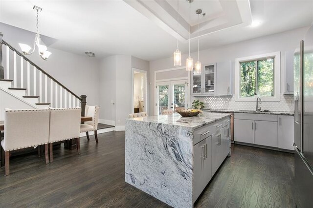 kitchen featuring pendant lighting, sink, white cabinets, dark hardwood / wood-style flooring, and a center island