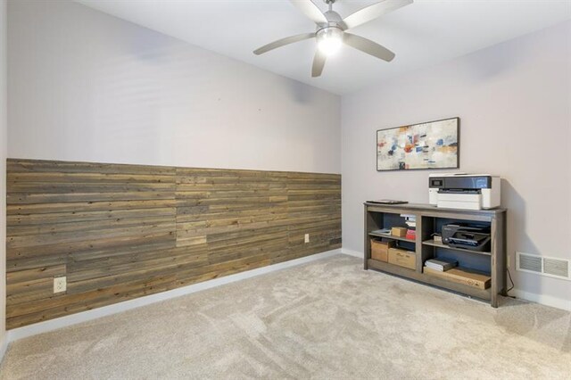 interior space featuring ceiling fan and wood walls