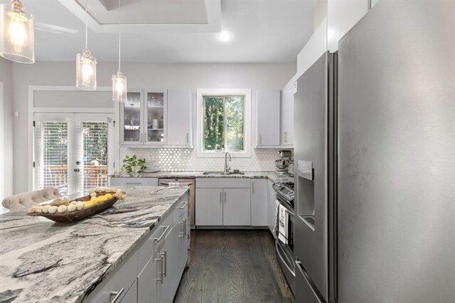 kitchen featuring decorative light fixtures, white cabinets, a center island, a tray ceiling, and stainless steel appliances