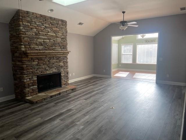 unfurnished living room with dark hardwood / wood-style flooring, ceiling fan, vaulted ceiling, and a stone fireplace