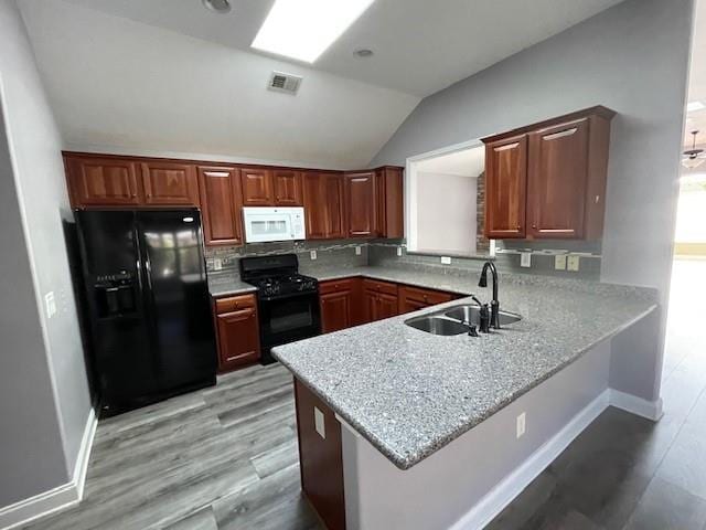 kitchen featuring sink, lofted ceiling with skylight, black appliances, and kitchen peninsula