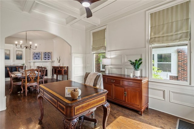 office space featuring arched walkways, beamed ceiling, ceiling fan with notable chandelier, dark wood-style floors, and a decorative wall