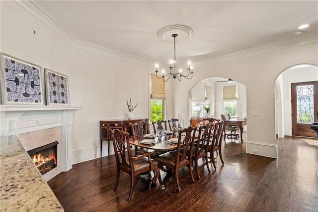 dining area with arched walkways, ornamental molding, and dark wood-style floors