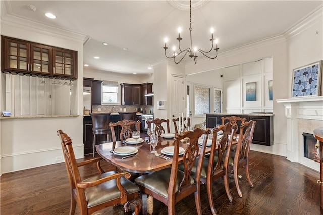 dining room with a chandelier, dark wood finished floors, ornamental molding, and recessed lighting
