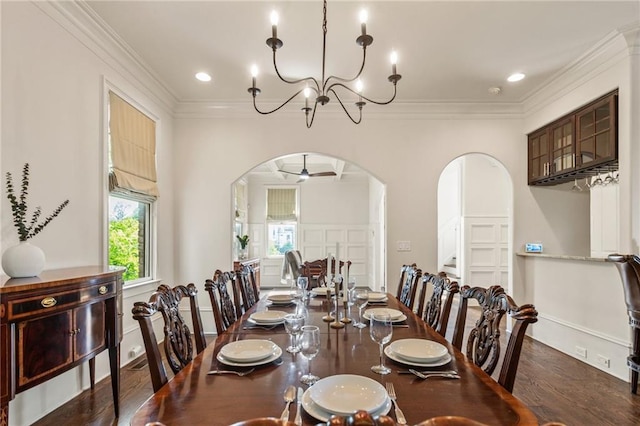 dining area with arched walkways, ceiling fan with notable chandelier, wood finished floors, and ornamental molding