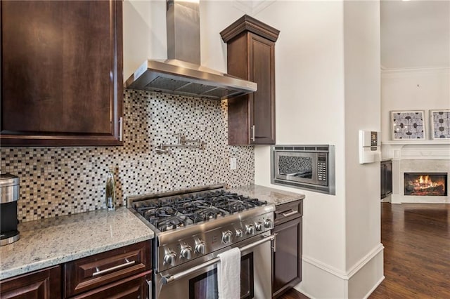 kitchen featuring wall chimney range hood, dark brown cabinets, appliances with stainless steel finishes, and ornamental molding
