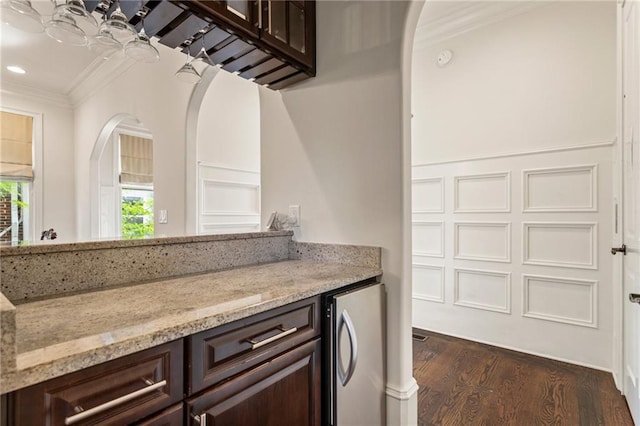 bar featuring freestanding refrigerator, dark wood-style flooring, ornamental molding, recessed lighting, and arched walkways