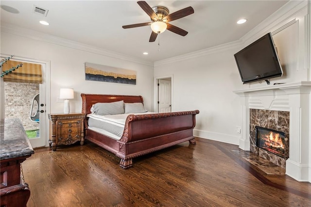 bedroom with baseboards, a high end fireplace, wood finished floors, and ornamental molding