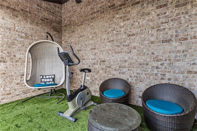 exercise room with carpet floors and brick wall
