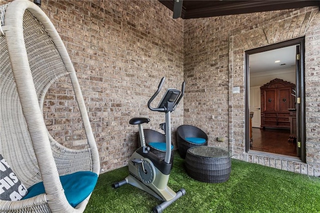 workout area featuring carpet floors, ornamental molding, and brick wall