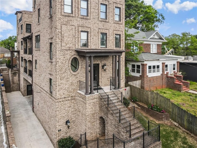 view of front of house featuring brick siding and fence