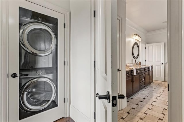 clothes washing area featuring laundry area, ornamental molding, and stacked washer / drying machine