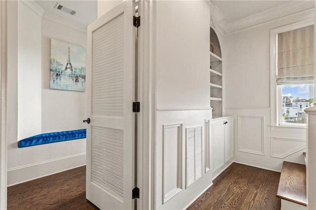 corridor with crown molding, dark wood-style flooring, built in shelves, and visible vents