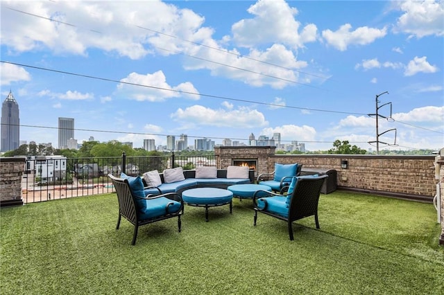 view of patio with fence, a city view, and an outdoor living space with a fireplace