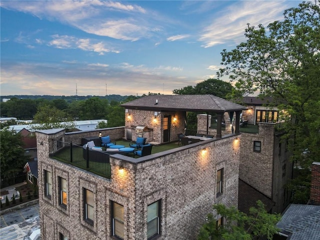 back of house with brick siding, a balcony, and area for grilling