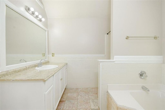 bathroom featuring vanity, tiled bath, and tile walls