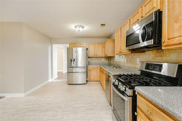 kitchen with sink, light brown cabinets, stainless steel appliances, light hardwood / wood-style floors, and decorative backsplash