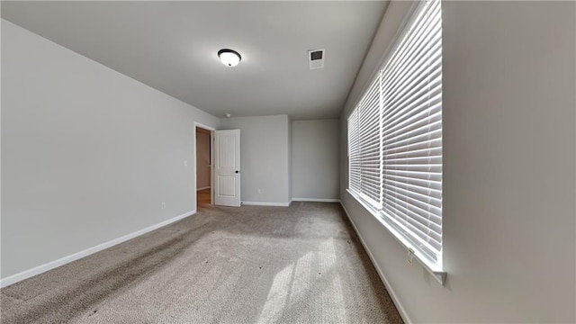 spare room featuring carpet flooring, visible vents, and baseboards