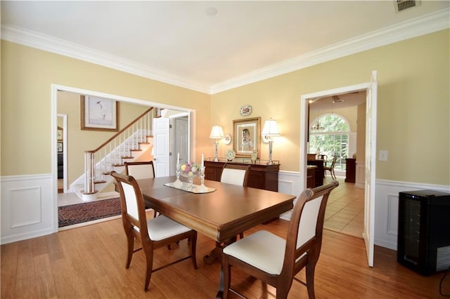 340 Channings Lake Dr, Lawrenceville, GA 30043 - dining space with stairway, a wainscoted wall, ornamental molding, and light wood-type flooring