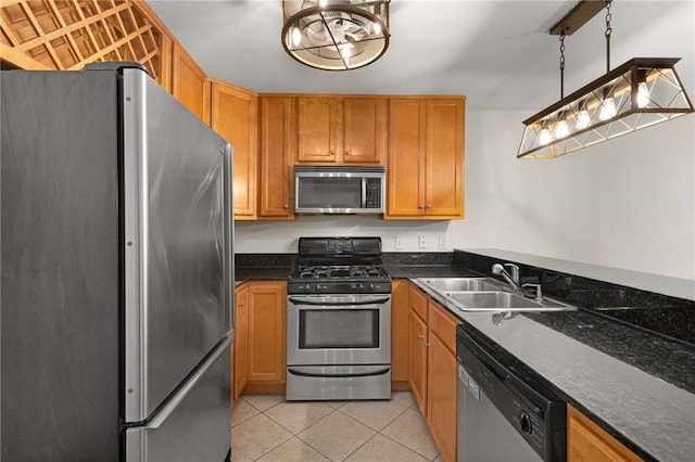 kitchen featuring pendant lighting, sink, dark stone counters, light tile patterned floors, and stainless steel appliances