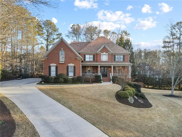 view of front of home with a porch, a front yard, and brick siding