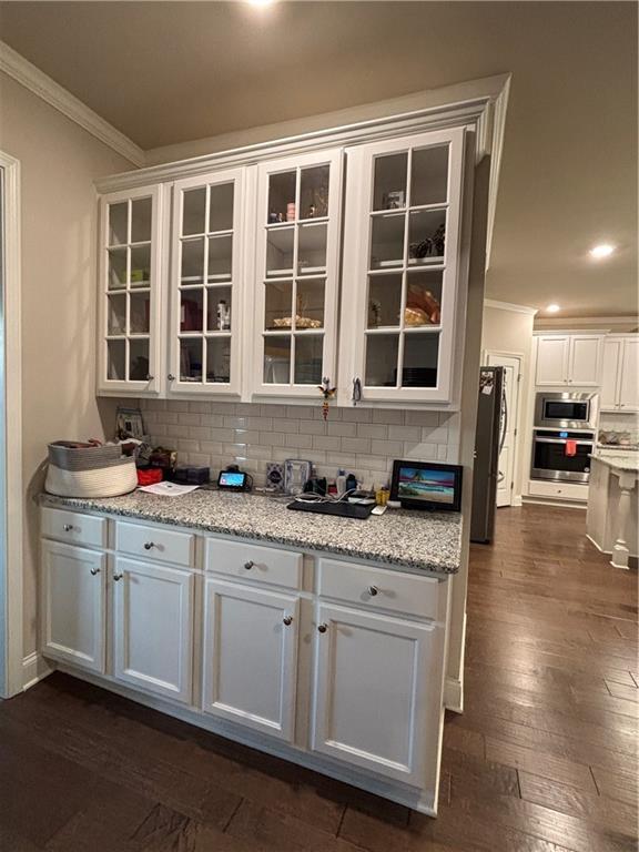 3566 Andover Way, Buford, GA 30519 - kitchen featuring stainless steel appliances, crown molding, dark wood-type flooring, white cabinets, and decorative backsplash