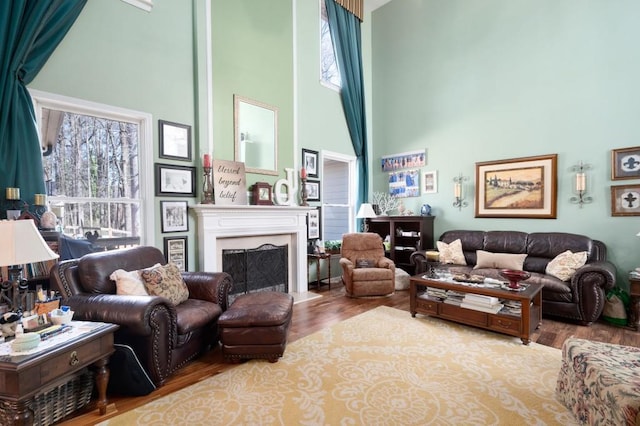 living room with a high ceiling, a fireplace with flush hearth, and wood finished floors