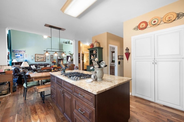 kitchen with open floor plan, dark brown cabinetry, dark wood-style floors, and stainless steel gas cooktop