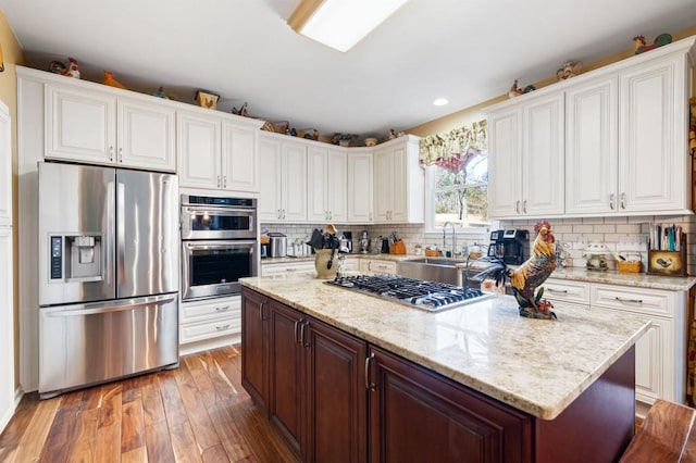 kitchen featuring a kitchen island, white cabinets, stainless steel appliances, and decorative backsplash