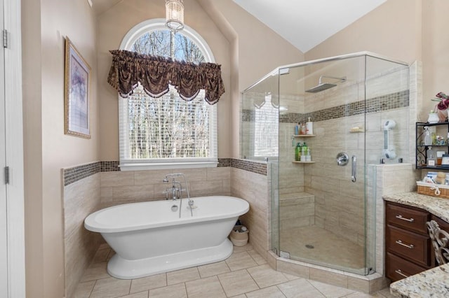 bathroom with vanity, a soaking tub, a stall shower, and vaulted ceiling