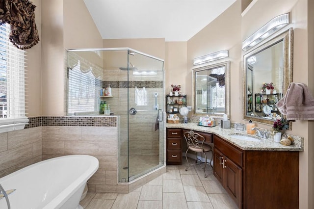 full bathroom featuring a soaking tub, a stall shower, vanity, and tile walls