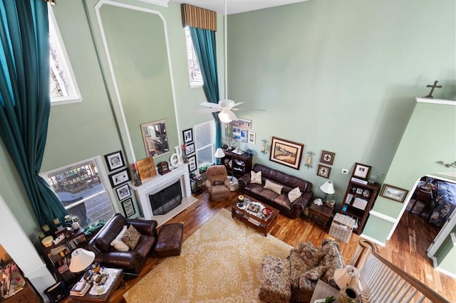 living area with a high ceiling, wood finished floors, and ceiling fan